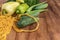 Green vegetables of zucchini, okra, cucumbers, bell pepper and a bunch of parsley lie next to a yellow string bag on a brown