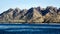 Green vegetation mountain landscape with white beach and blue coastline sea at its foot.