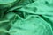 Green velour fabric texture. Wavy folds background. Fragment of a drapery dark green cloth material