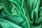 Green velour fabric texture. Wavy folds background. Fragment of a drapery dark green cloth material