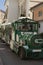 Green walking tourist train on wheels driven along old street pe