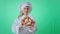 Green wall studio baker woman with a cute large smile playing with a fresh pretzel in front of the camera she moving