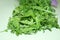 Green washed arugula laid out on white table, closeup, selective focus