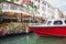 Green water channel with gondolas and colorful facades of old medieval buildings in the sun in Venice, Italy.