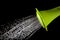 Green watering can pouring water with high speed shutter isolate