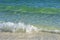 The green wave comes from the ocean, breaks into splashes on the shore and foams