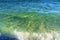The green wave comes from the ocean, breaks into splashes on the shore and foams