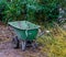 Green wheelbarrow in a garden, working on garden maintenance, equipment for the backyard