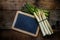 Green and white asparagus and a blank blackboard on a rustic woo