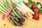 Green white asparagus with fresh strawberries on bright wood. Healthy cooking concept.