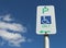 Green white and blue Wheelchair Only Parking sign in a cloudy blue sky