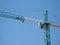 Green and white construction hoisting crane over c
