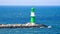 green white lighthouse on the Warnow River in Rostock on the Baltic Sea. Waves on the stone edge