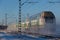 Green and white passenger train in snow dust passing