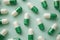 Green and white pills arranged on a mint color background