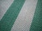 Green and white synthetic burlap, close-up. Polyethylene material. Interlacing of polyethylene fibers and threads. Beach mat or
