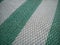 Green and white synthetic burlap, close-up. Polyethylene material. Interlacing of polyethylene fibers and threads. Striped beach