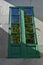 Green window with reflected green tree and blue sky. Spain.