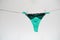 Green women`s thong panties on a clothesline fastened with white pegs