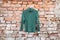 Green womens jacket hanging on a brick old wall outside