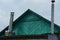 Green wooden attic in a rural house with two metal chimneys