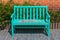 Green wooden bench place on concrete walkway or footpath at public park.