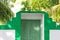 Green wooden door of a maldivian house with palms