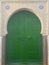 A green wooden door surrounded by ornaments in the ancient city of Tetouan, Morocco