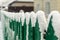 Green wooden fence under the snow, snowflakes fall, selective focus