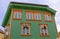 Green wooden house in Norwegian style with orange windows
