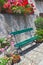 Green wooden seat in red, pink flowers and plants