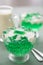 Green woodruff Jell-O and vanilla sauce in glass bowl