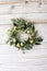 Green wreath with easter quail eggs and flowers on wooden background