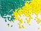 Green and yellow masterbatch granules on white background