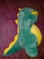 The green and yellow medium-sized dinosaur doll looks very cute in the morning, seen from the right side