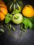 Green, yellow and orange pumpkin with buds , stems and leaves on dark slate table