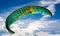 Green and yellow paragliding sail in the air against a blue sky backdrop i