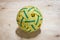 Green and yellow rattan ball on wooden floor.