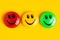Green yellow and red round magnet with smile in a row on a yellow background