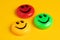 Green yellow and red round magnet with smile in a row on a yellow background