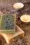 Green and yellow soaps with a scented candle in a romantic setting. Spa concept on wooden background. Wellness concept