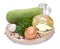 Green zucchini, garlic, a bottle of vegetable oil, parsley, onion, mixed peppercorns against the background of a round wooden