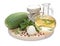 Green zucchini, garlic, a bottle of vegetable oil, parsley, onion, mixed peppercorns against the background of a round wooden