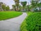 Greenery bush and trees in garden with gray curve pattern walkway, sand washed finishing on concrete paving and brown gravel