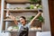 Greengrocer wearing apron raising hand holding calculator in vegetable shop