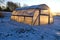 Greenhouse hothouse on farm field on snow and winter sunrise