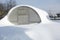 Greenhouse in the snow. High snowdrifts in the winter dacha. Snowy vegetable garden in the winter