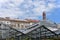 Greenhouses made of steel construction in front of residential buildings and chimney.