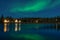 Greenish Aurora Borealis over illuminated Tipi near a lake, Yellow knife village