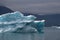 Greenland, blue iceberg with lightblue spots inside of it andwith dramatic mood of the sky in the atlantic ocean